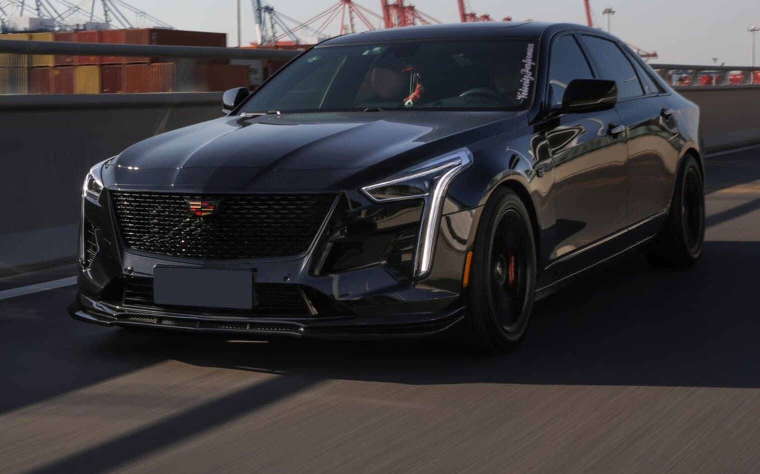 A black luxury sedan driving on a highway in daylight